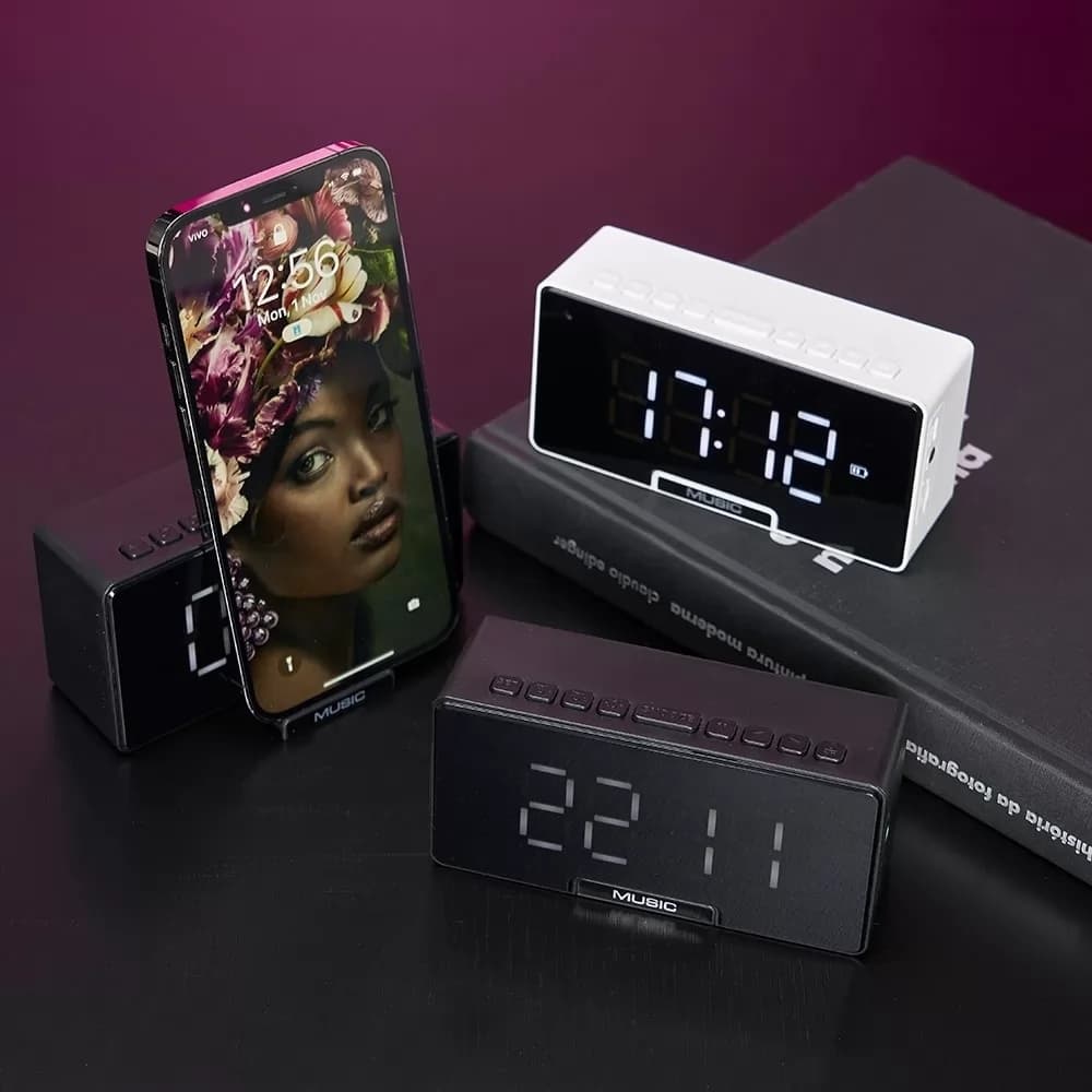 Caixa de som multimídia com relógio digital nas cores branca e preta, com display iluminado e suporte para celular