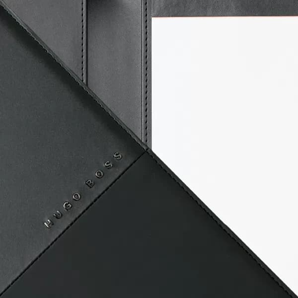 Detalhe interno de pasta A5 preta com costura reforçada, bloco de papel e logo Hugo Boss