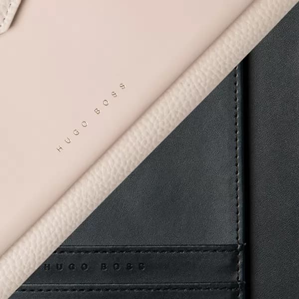 Pasta A5 sortida em detalhe aproximado nas cores bege e preta com textura e logo Hugo Boss