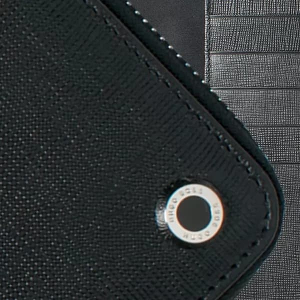 Close de pasta para arquivo A4 preta com textura granulada, costura na borda e aplique de metal circular