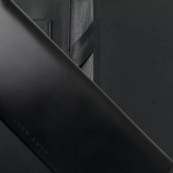 Detalhe em close-up de pasta executiva preta em material sintético com acabamento texturizado
