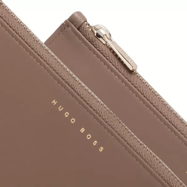 Detalhe aproximado da pasta A6 taupe com zíper metálico e logo dourado Hugo Boss