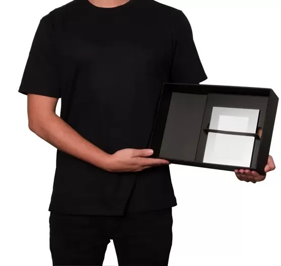 Homem vestindo camiseta preta segurando a caixa aberta do kit com porta-retrato
