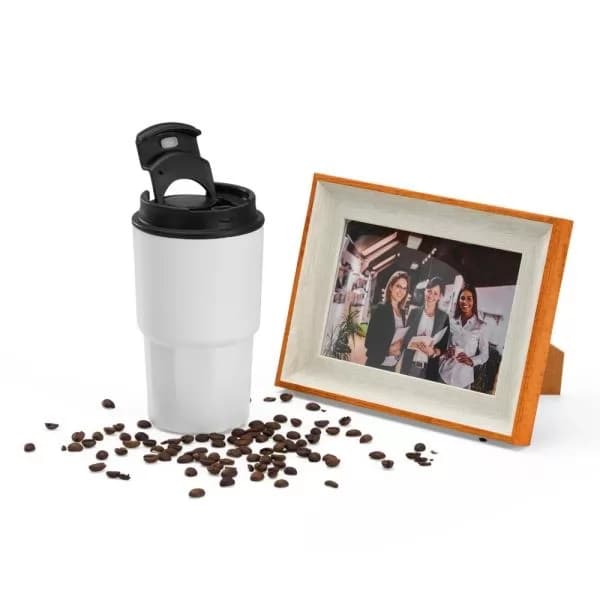 Kit copo térmico branco com tampa preta e porta-retrato de madeira ao lado de grãos de café