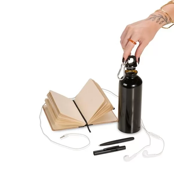 Kit boas-vindas com squeeze preto segurado pela tampa, caderno aberto, fone de ouvido branco e caneta