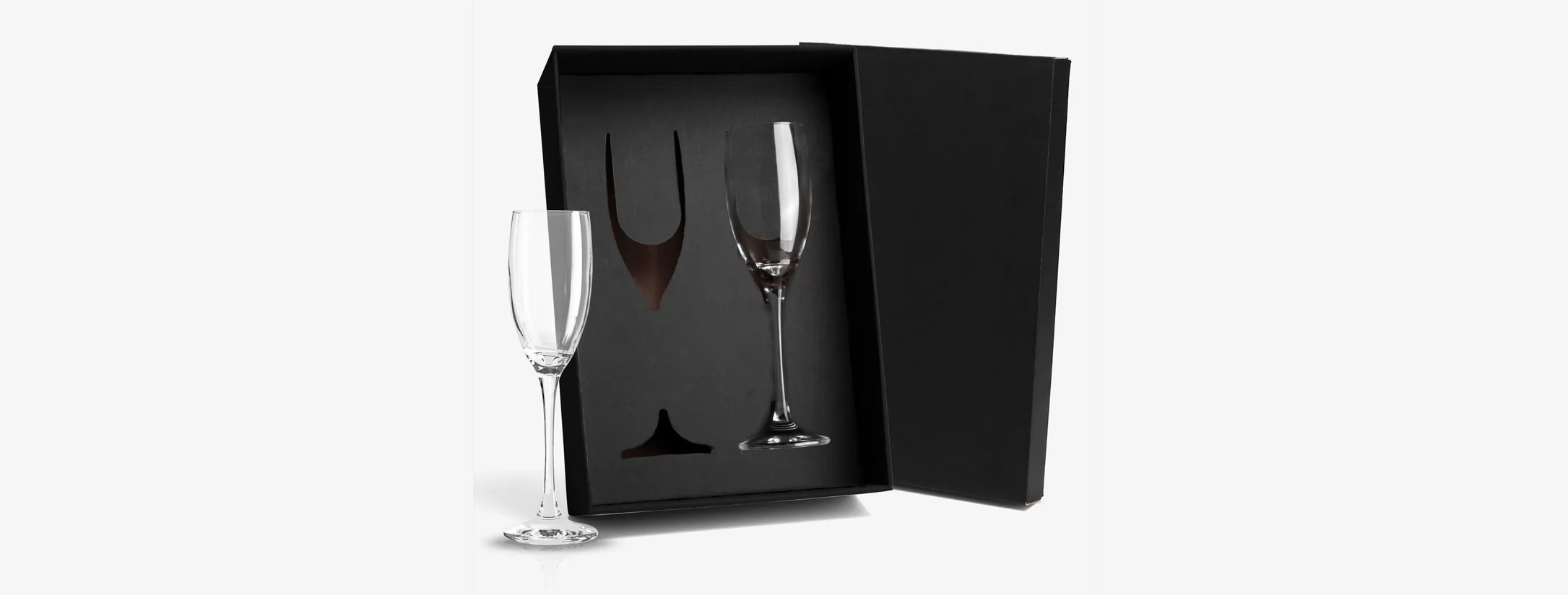 Jogo de taças de vidro para champagne transparentes ao lado de estojo preto aberto