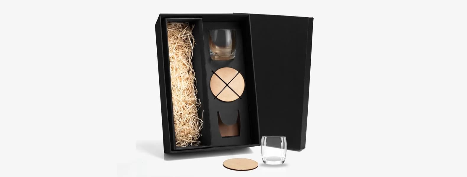 Jogo de copos de vidro para whisky e porta-copos acomodados em caixa preta de presente