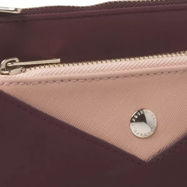 Detalhe em close da bolsa Bird bordô com acabamento bege, zíper e botão metálico