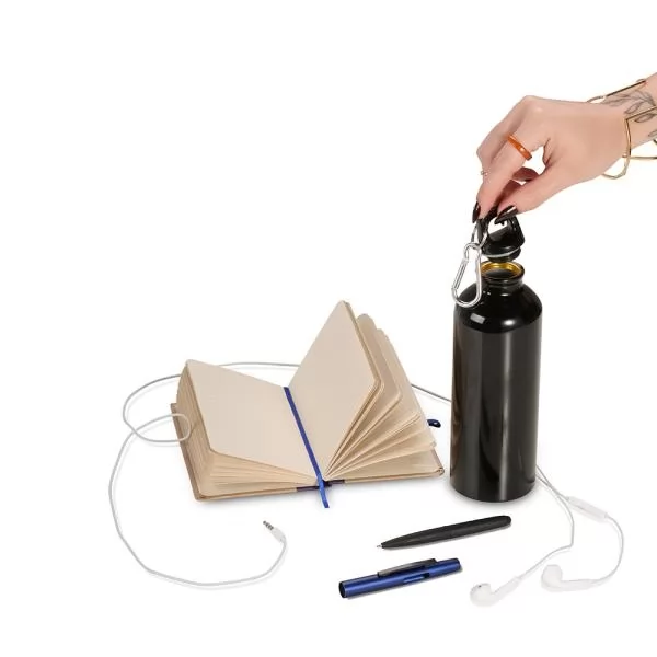 Kit com squeeze metálica preta, caderno aberto com fita azul, caneta e fones de ouvido brancos